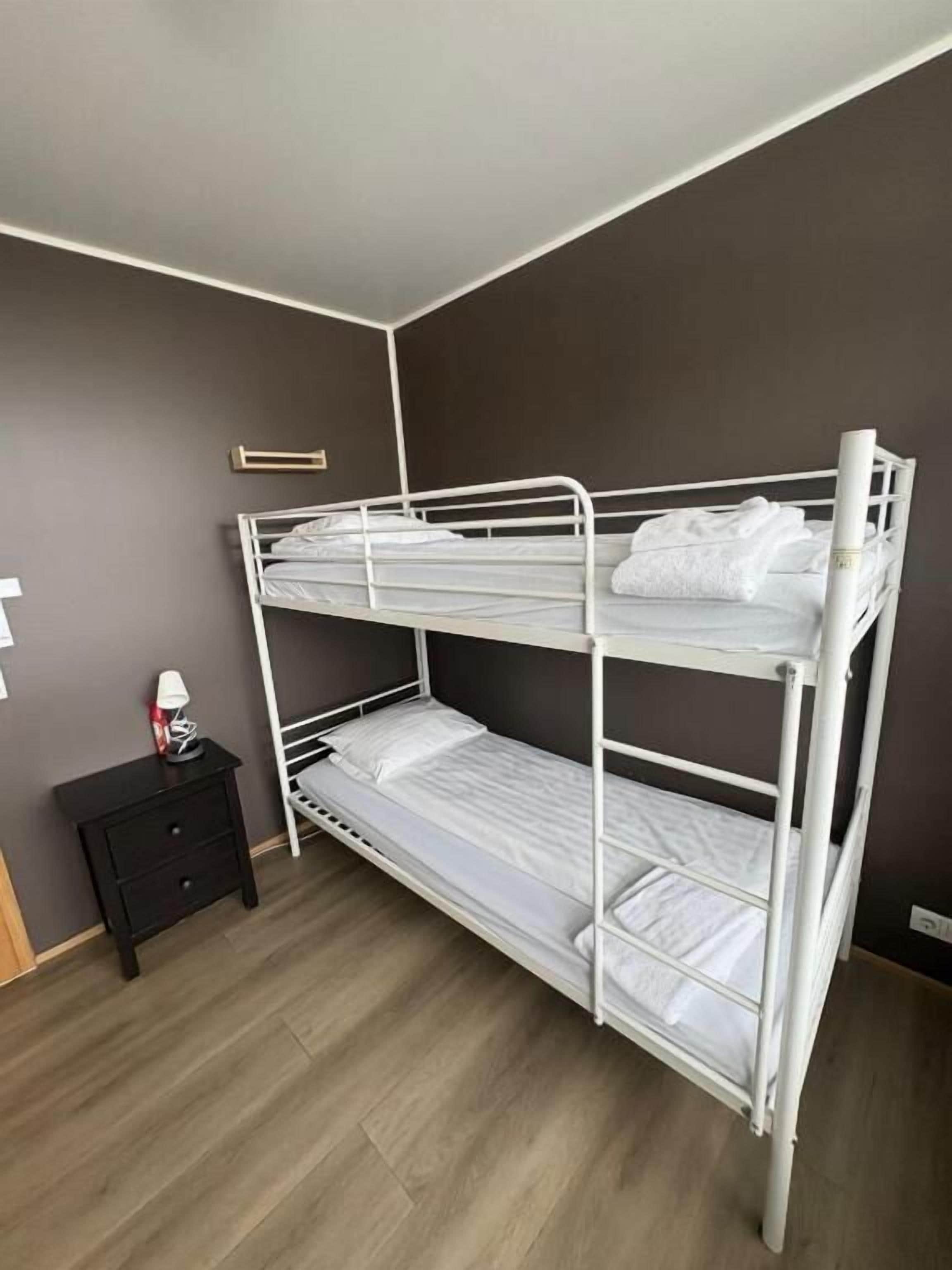 Uma cama beliche em quarto com parede escura e chão de madeira.
