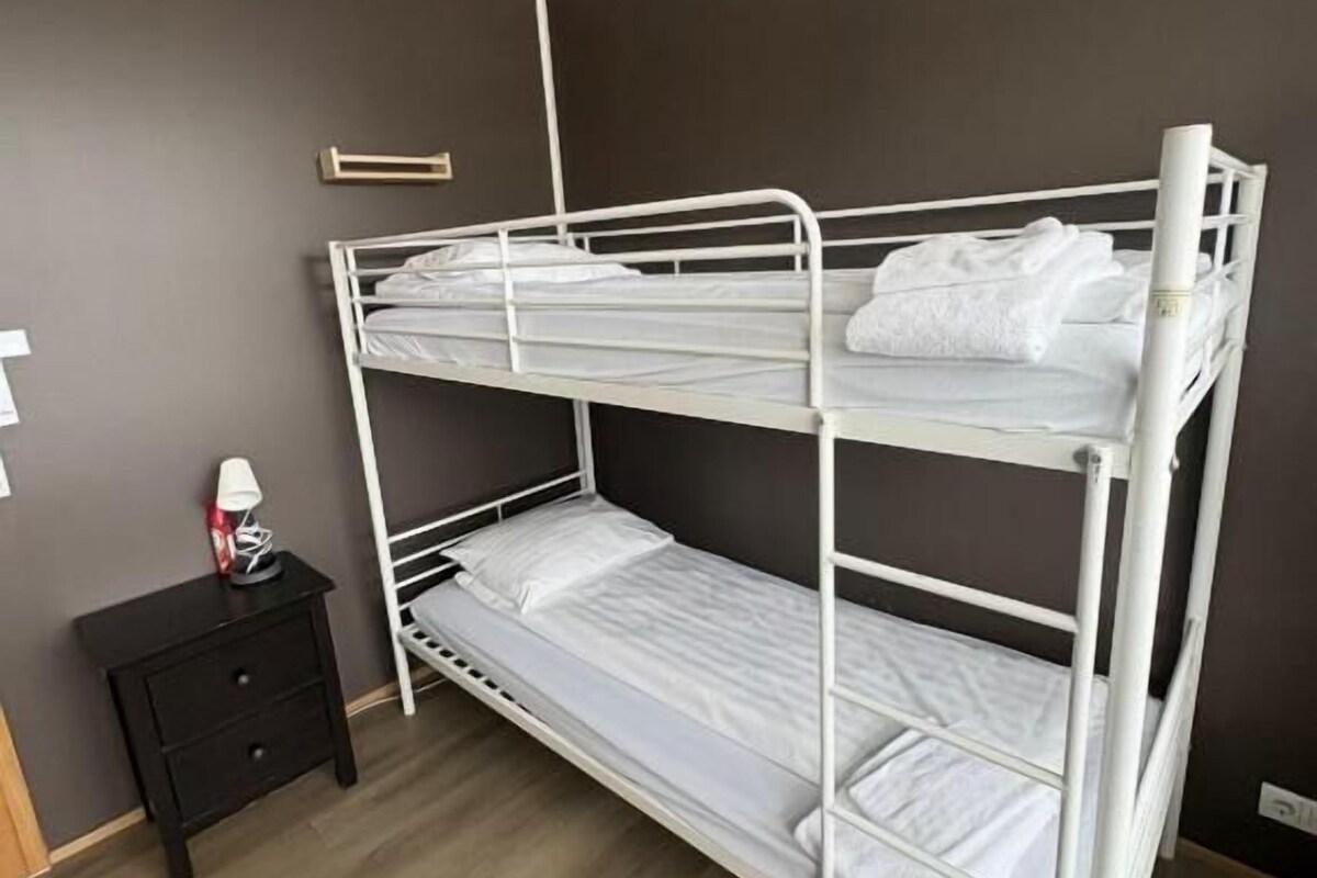 Ein Stockbett in einem Zimmer mit dunkler Wand und Holzboden.