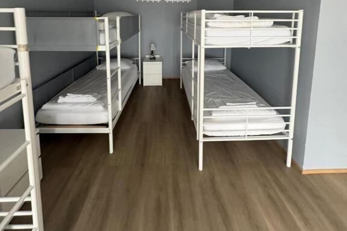 Ein Zimmer mit Etagenbetten, einem kleinen Nachttisch und einer Wandleuchte.