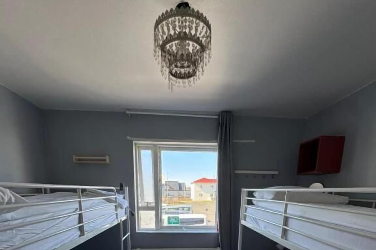 Ein Zimmer mit Etagenbetten, einer Kristallleuchtre, einem Fenster mit Blick und einer Heizung.