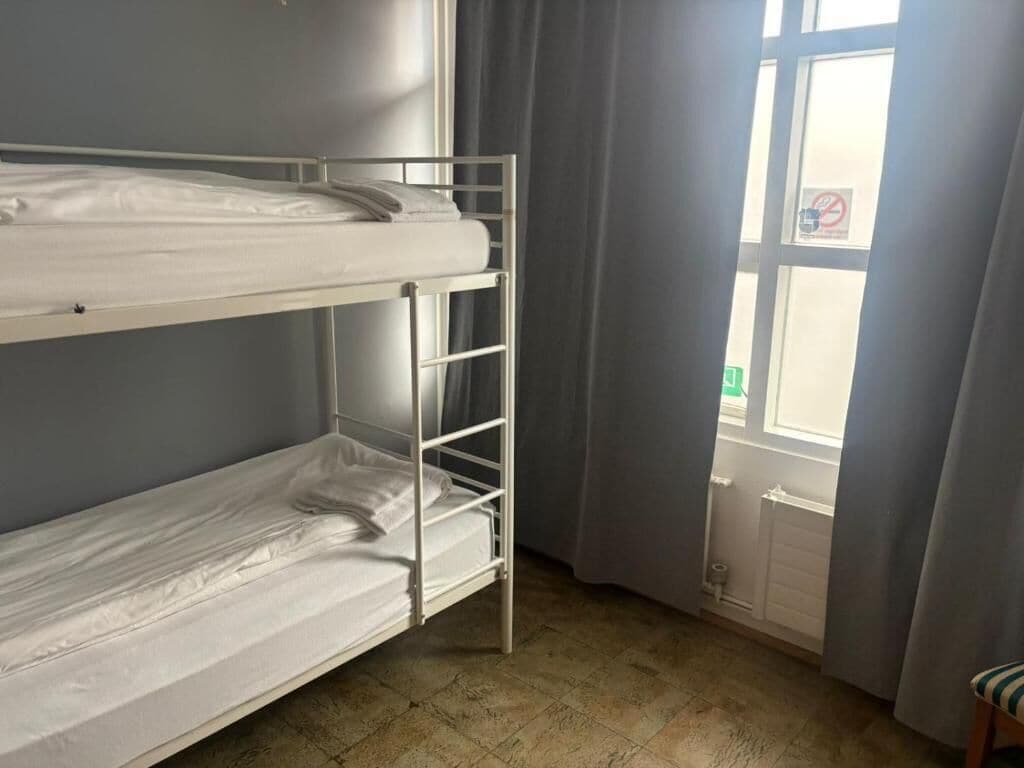 A bunk bed room with a window and curtains.