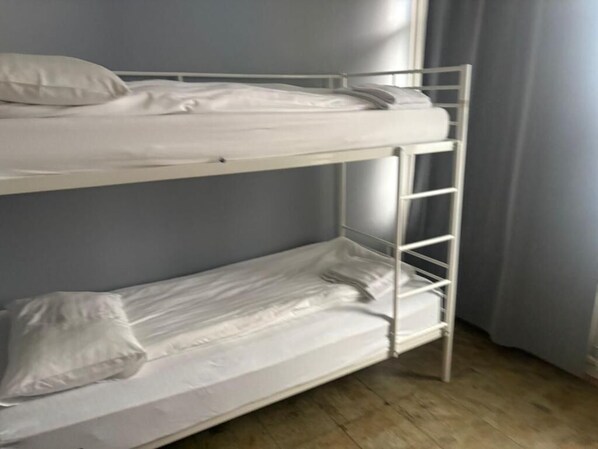 A bunk bed with white bedding and a ladder.