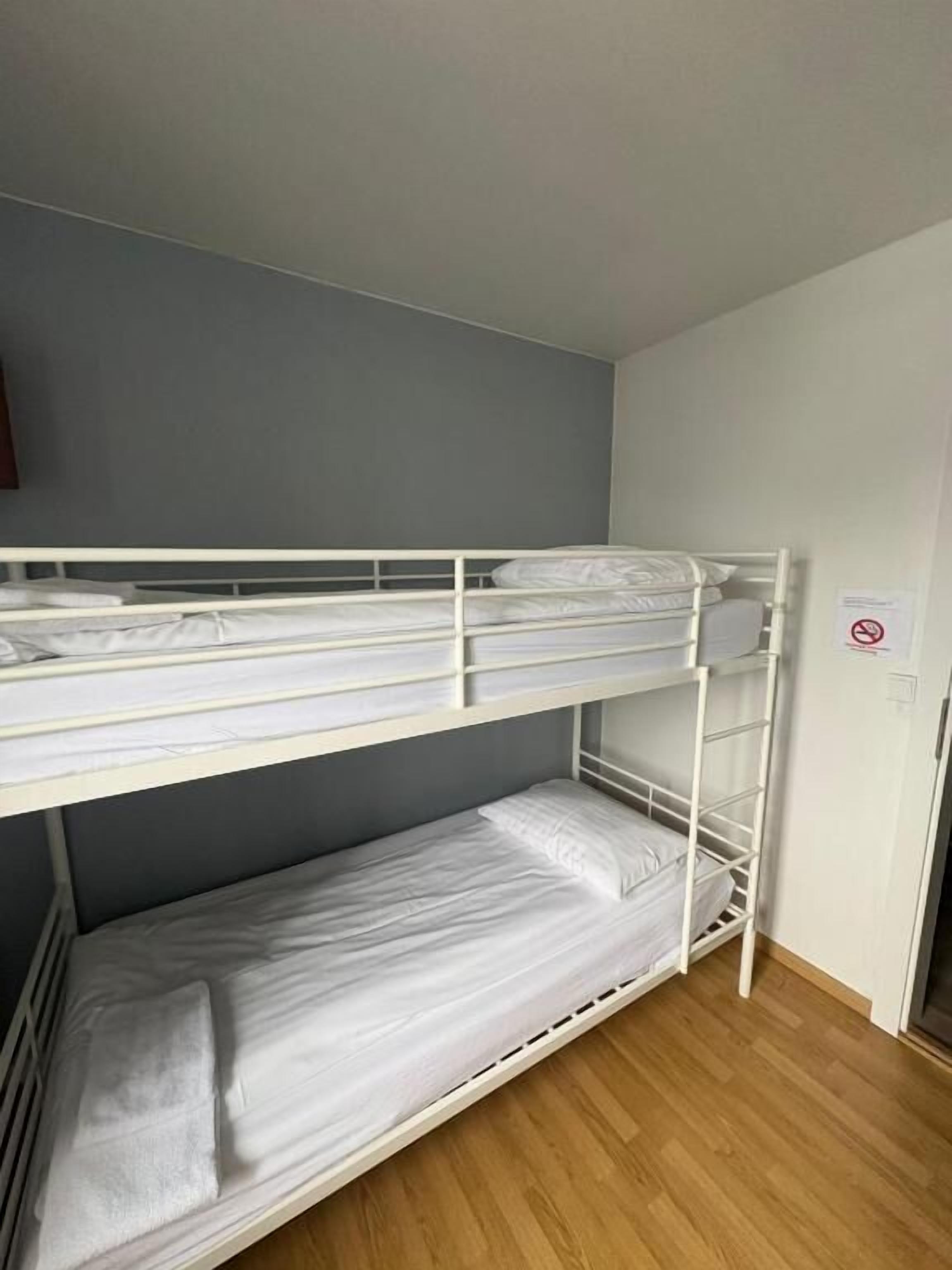 A bunk bed in a room with a grey wall and wooden flooring.
