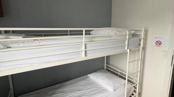 A bunk bed in a room with a grey wall and wooden flooring.