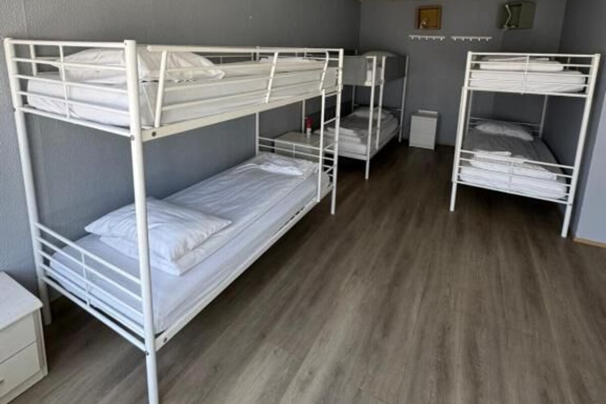 Ein Zimmer mit Etagenbetten, einem kleinen Nachttisch und einem Wandheizgerät.