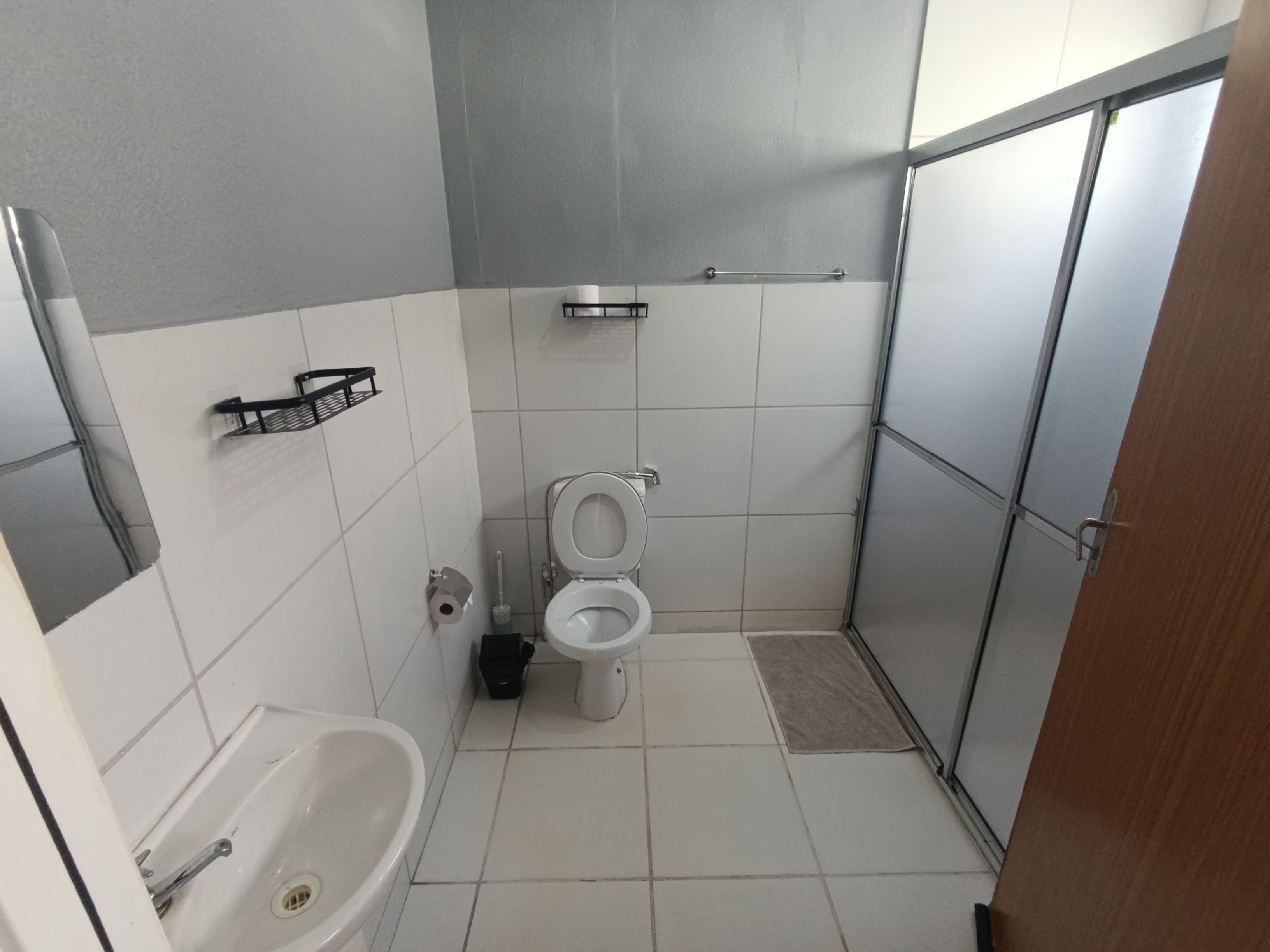 A bathroom with a toilet, sink, and shower area.