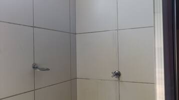 Box de chuveiro revestido com azulejos, com chuveiro manual e painel de controle.