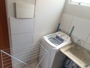 A compact laundry area with a washing machine, a drying rack, and a sink. - Apartment with two bedrooms in the bedroom (Macapá)