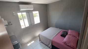 A bedroom with a bed, a window, and an air conditioning unit.