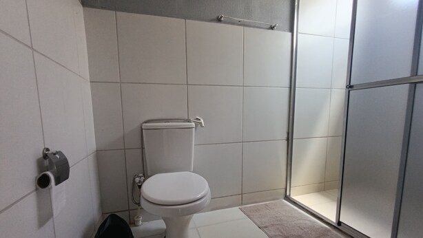 Ein Badezimmer mit Toilette, Duschbereich und Handtuchhalter.