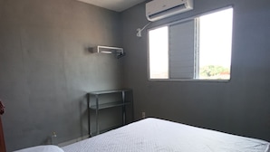 Ein Schlafzimmer mit einem Einzelbett, einem Fenster und einer Klimaanlage.