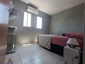 A bedroom with a bed, a window, an air conditioner, and a bedside lamp. - Apartment with two bedrooms in the bedroom (Macapá)