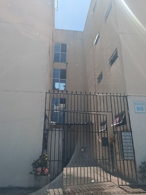 A building with a gated entrance, a sign indicating 'Bloco 60', and a small garden area with flowers. - Apartment with two bedrooms in the bedroom (Macapá)