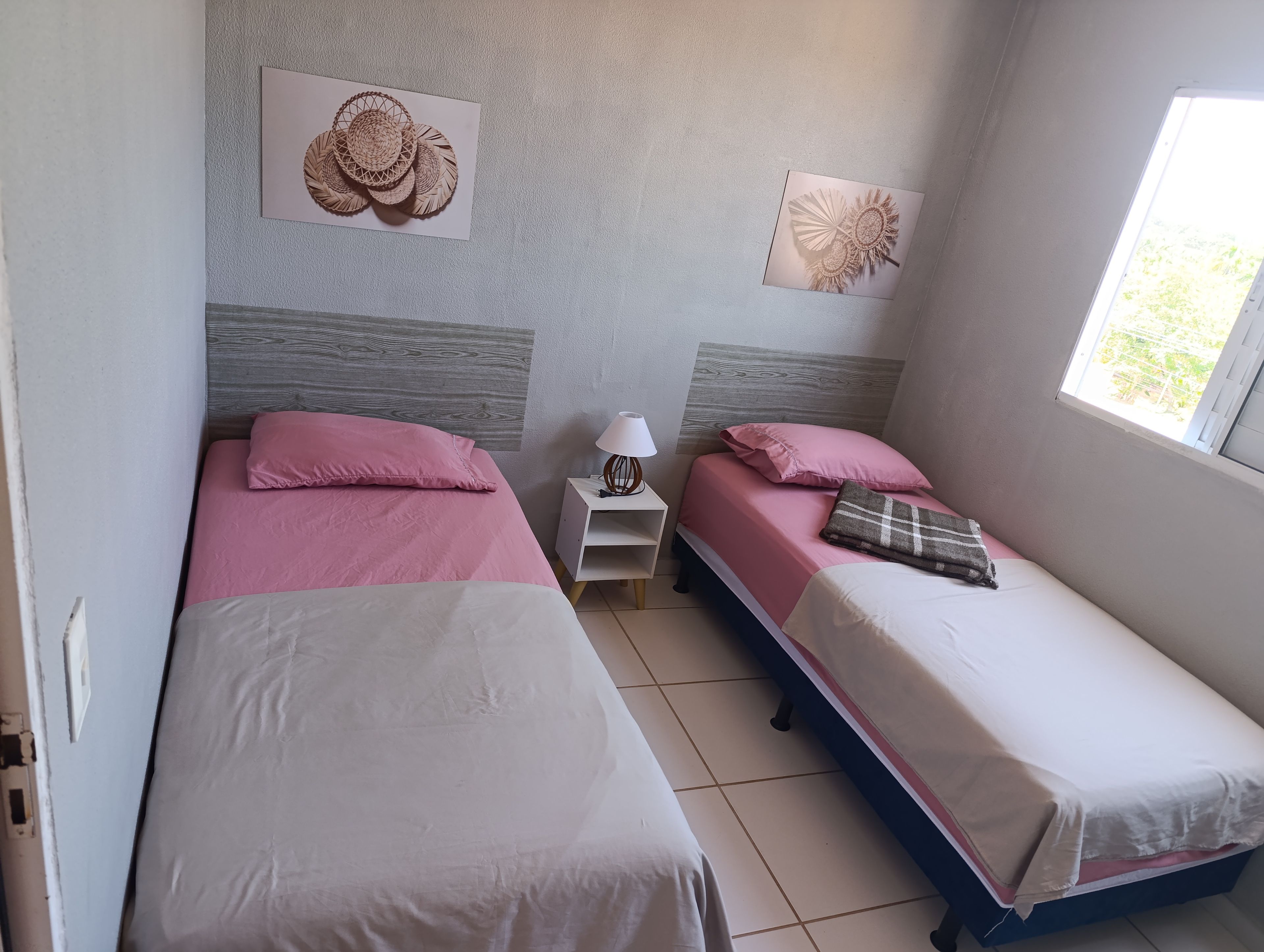 A bedroom with two beds, a nightstand, and wall art.