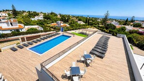 A rooftop pool with sun loungers and a table, surrounded by a wooden deck and a view of the sea and buildings. - Villa Carvoeiro, luxury 10 Bedroom, heated pool, games, BBQ (Carvoeiro)