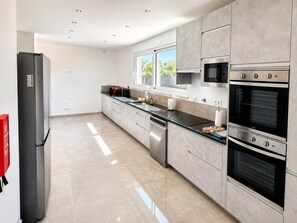 A modern kitchen with stainless steel appliances, a window, and a dishwasher. - Villa Carvoeiro, luxury 10 Bedroom, heated pool, games, BBQ (Carvoeiro)