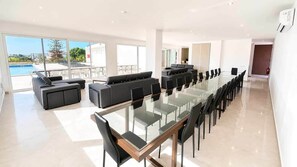 A modern hotel room with a glass dining table, black chairs, a sofa, and a view of a pool. - Villa Carvoeiro, luxury 10 Bedroom, heated pool, games, BBQ (Carvoeiro)