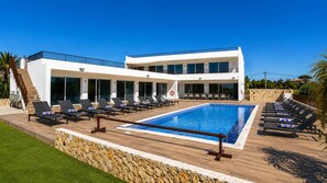 A modern two-story building with a swimming pool, outdoor seating, and a stone retaining wall. - Villa Carvoeiro, luxury 10 Bedroom, heated pool, games, BBQ (Carvoeiro)