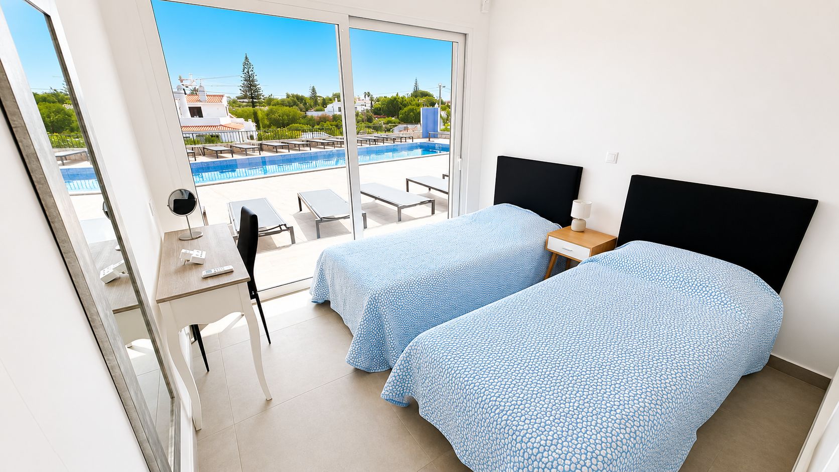 Une chambre d’hôtel avec deux lits, un bureau, une chaise et une vue sur une piscine.