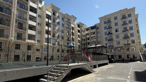 Ein mehrstöckiges Wohngebäude mit Balkonen, einer Fußgängerbrücke und einem Spielplatz.