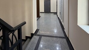 Ein Flur mit poliertem Boden, einer Treppe links und einer Tür am Ende.