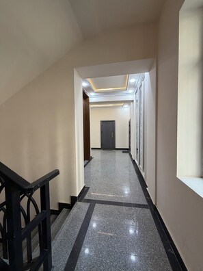 Ein Flur mit poliertem Boden, einer Treppe links und einer Tür am Ende.