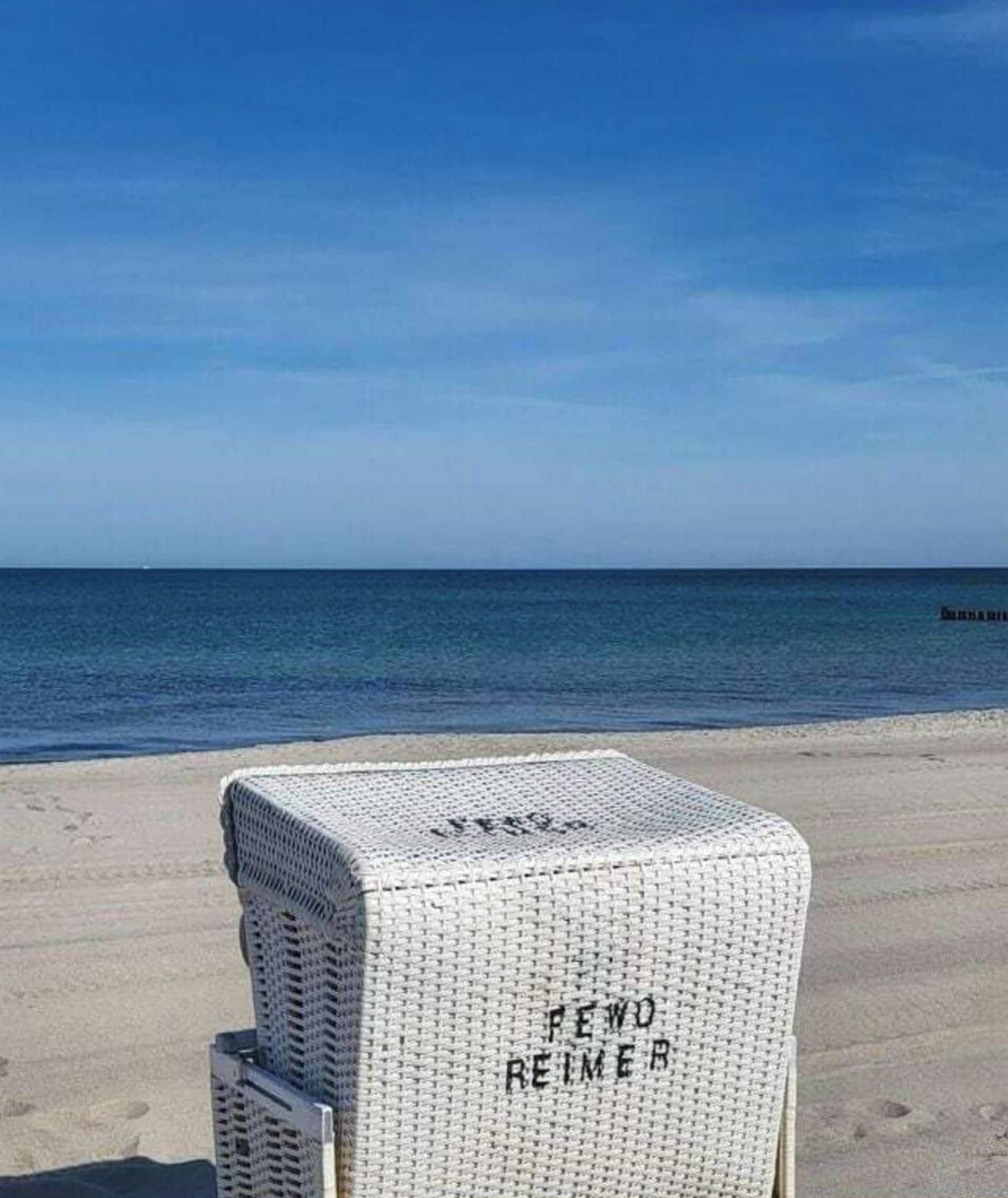 A beach with a white chair labeled 'FEWO REIMER' in the foreground.