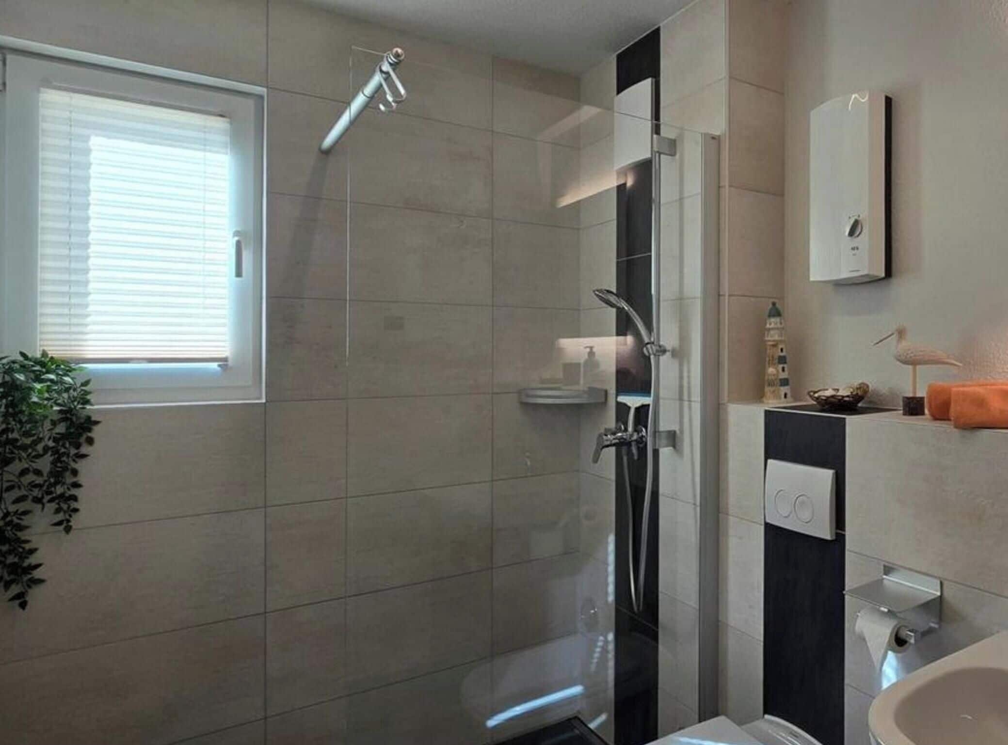 Ein modernes Badezimmer mit Duschkabine aus Glas, Waschbecken und Toilette.