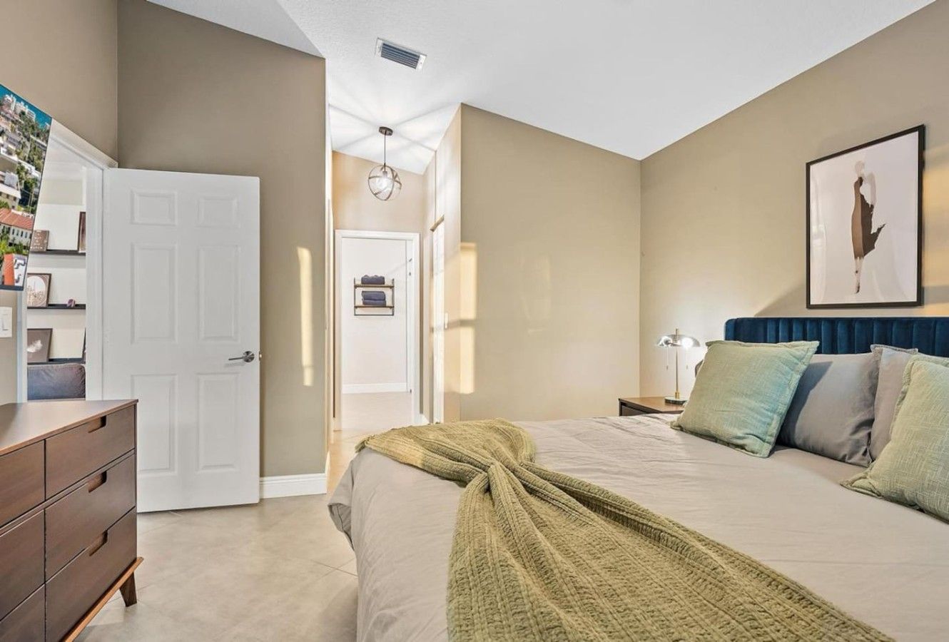 A bedroom with a bed, bedside tables, a dresser, and a door.