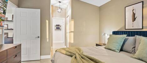 A bedroom with a bed, bedside tables, a dresser, and a door.