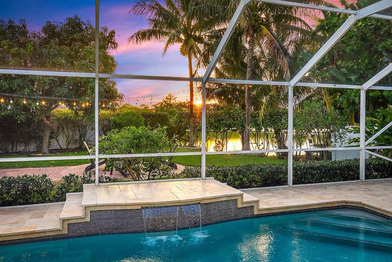Piscina con vistas a palmeras y al atardecer.