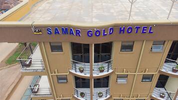 Um hotel de vários andares com varandas, um letreiro com a inscrição 'SAMAR GOLD HOTEL' e um logotipo acima do letreiro.