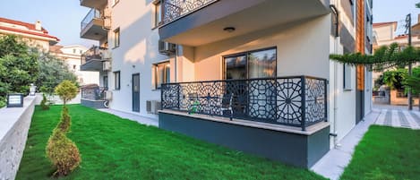 A multi-story residential building with a balcony featuring intricate metal railings.