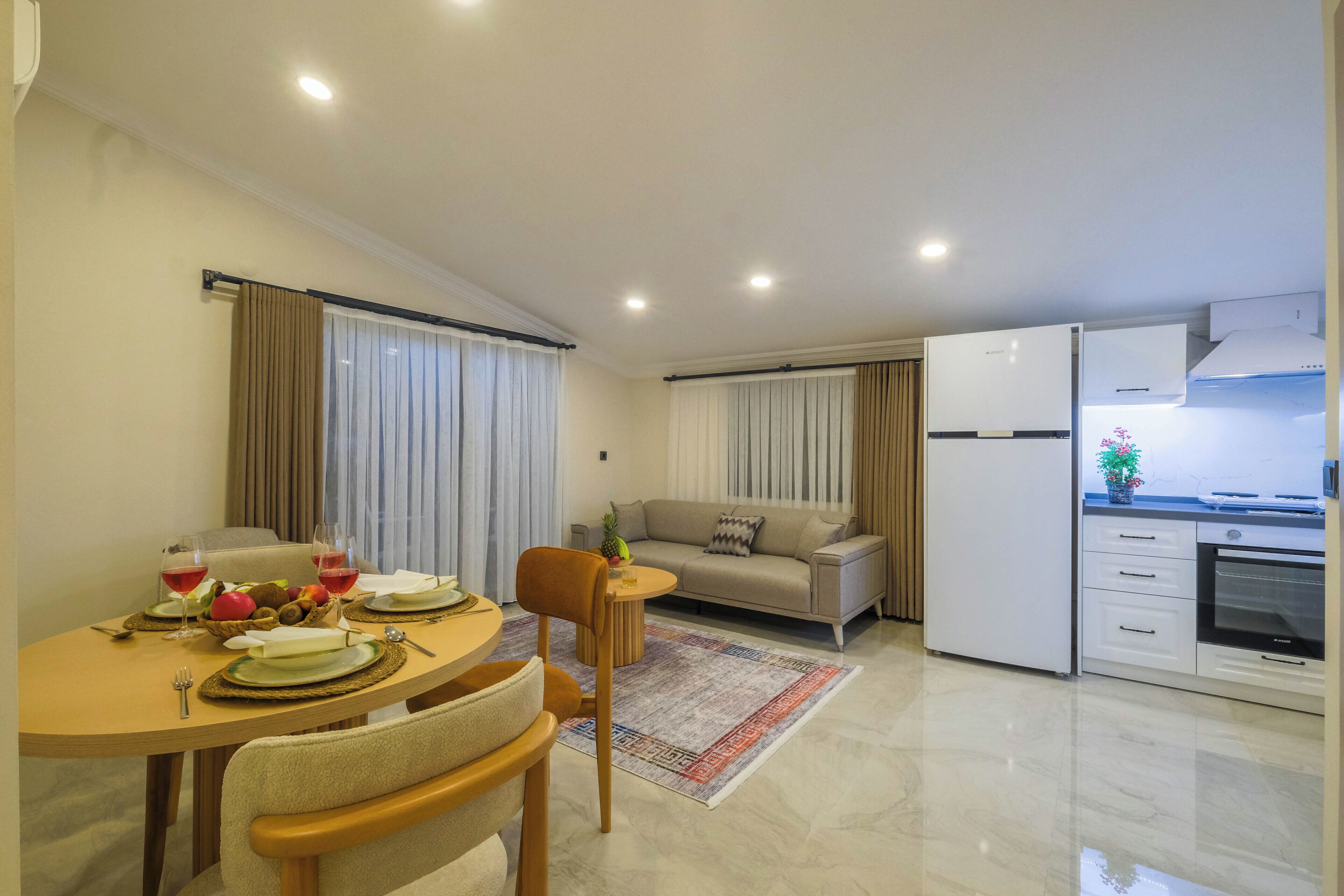 Un espacio habitable moderno con comedor, sofá, cocina y refrigerador.