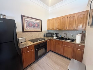 A compact kitchen with wooden cabinets, a built-in microwave, a toaster, and a sink.