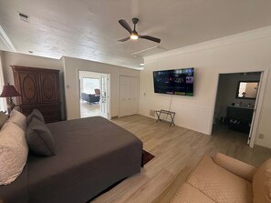 A modern living room with a large bed, a television mounted on the wall, and a ceiling fan. - Hot Tub, Lake View, Eureka Springs Lakehouse (Eureka Springs)