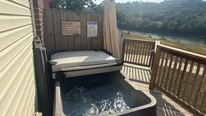 Uma banheira de hidromassagem com deck de madeira e vista para um lago.