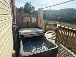 Ein Whirlpool mit einer Holzterrasse und Blick auf einen See.