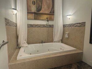 Ein Badezimmer mit einer freistehenden Badewanne, einer Duschbrause und einem Seifenspender.