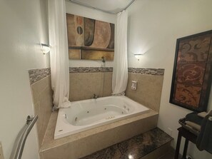 A bathroom with a freestanding bathtub, a shower curtain, and a wall-mounted light fixture. - Hot Tub, Lake View, Eureka Springs Lakehouse (Eureka Springs)