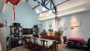 A dining area with a wooden table and chairs, a television, and a bookshelf. - Mutianyu Great Wall View Lodge (Huairou)