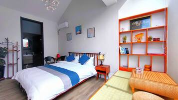 Un dormitorio moderno con cama, mesita de noche y un pequeño sofá. Hay una estantería con objetos decorativos y un estante montado en la pared.