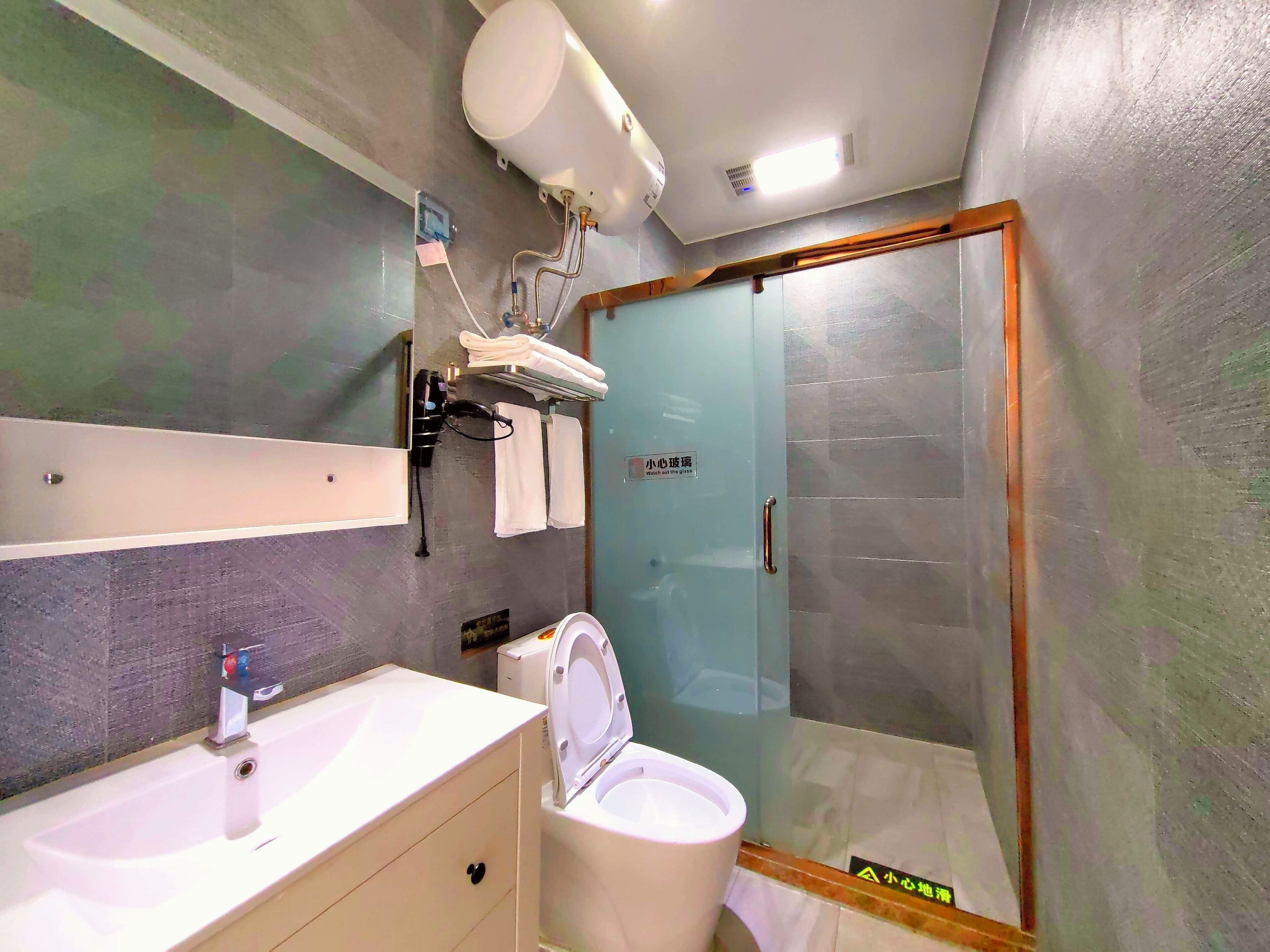 Ein Badezimmer mit einem weißen Waschbecken, einer Toilette und einer gläsernen Duschkabine.