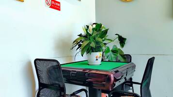 A table with a green tablecloth, two chairs with woven seats, and a potted plant on the table.