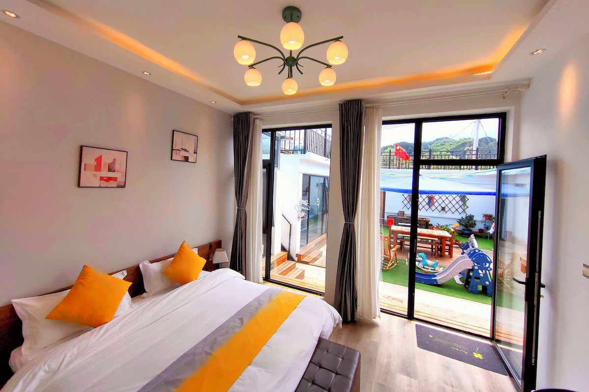Una habitación de hotel con cama, un balcón y vistas a un puente, y una lámpara en el techo.