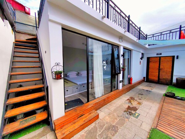 A modern building with a staircase, large sliding glass doors, and a balcony.