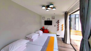 A hotel room with a bed, a flat-screen TV, a wall-mounted TV, a window with curtains, and a ceiling light fixture. - Mutianyu Great Wall View Lodge (Huairou)