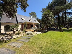 A house with a covered porch, a stone pathway, and a well-maintained lawn. - Vrbo Property (Molac)