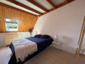 A bedroom with a bed, bedside table, lamp, and a wooden ladder. - Large house with a private pond (Molac)