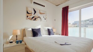Et hotelværelse med en stor seng, to sengeborde, to lamper, et billede på væggen og udsigt fra vinduet.